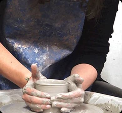 Hands shaping clay on a pottery wheel during a workshop