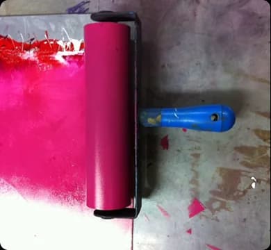 A vibrant pink printmaking roller on a press