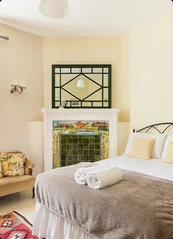 A bright bedroom with fireplace inside one of the Upper Court cottages